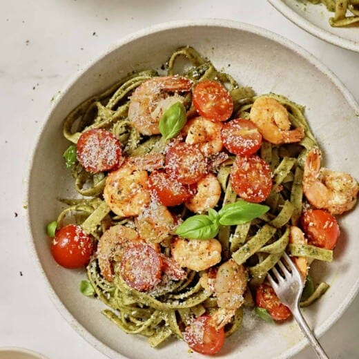 Pesto pasta with shrimp, tomatoes, and parmesan cheese.