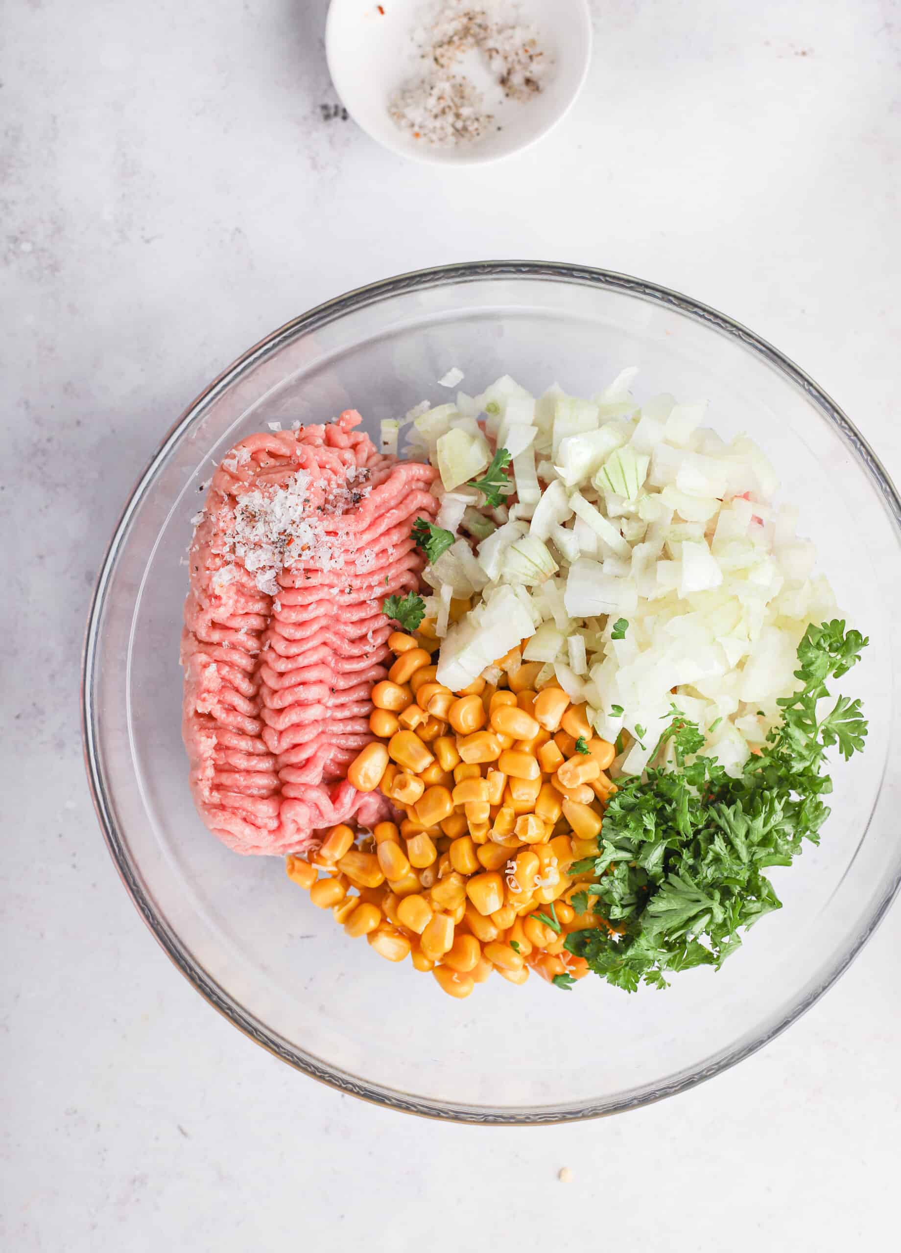 Ground turkey, corn, chopped onions and cilantro in a glass mixing bowl