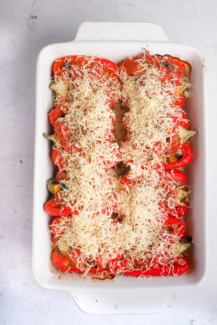 Shredded Monterey Jack cheese sprinkled over a dish full of cooked Southwestern stuffed peppers