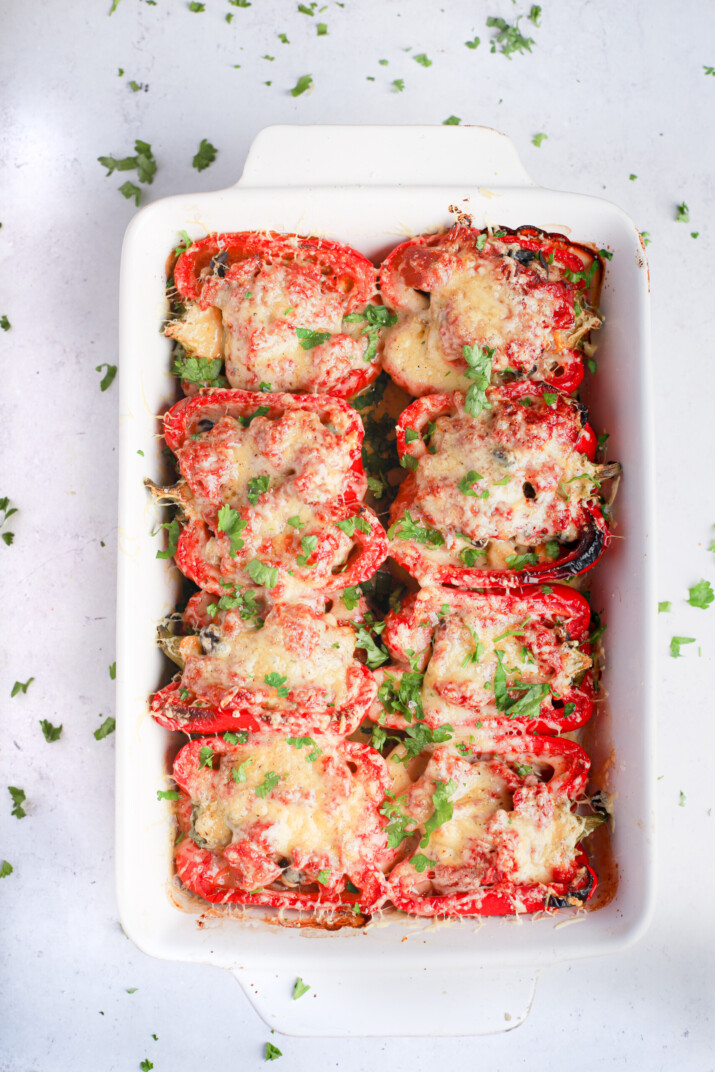A white baking dish containing turkey stuffed peppers with melted cheese and chopped cilantro on top