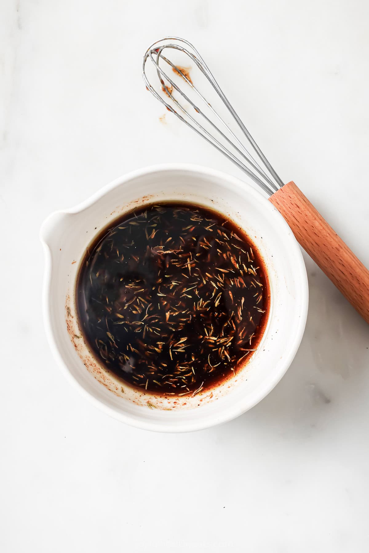 This recipe for balsamic vinaigrette is easy to whip up and the sweet, tangy flavor brings out the best in any salad—and so much more! Overhead view of balsamic vinaigrette in small bowl with whisk