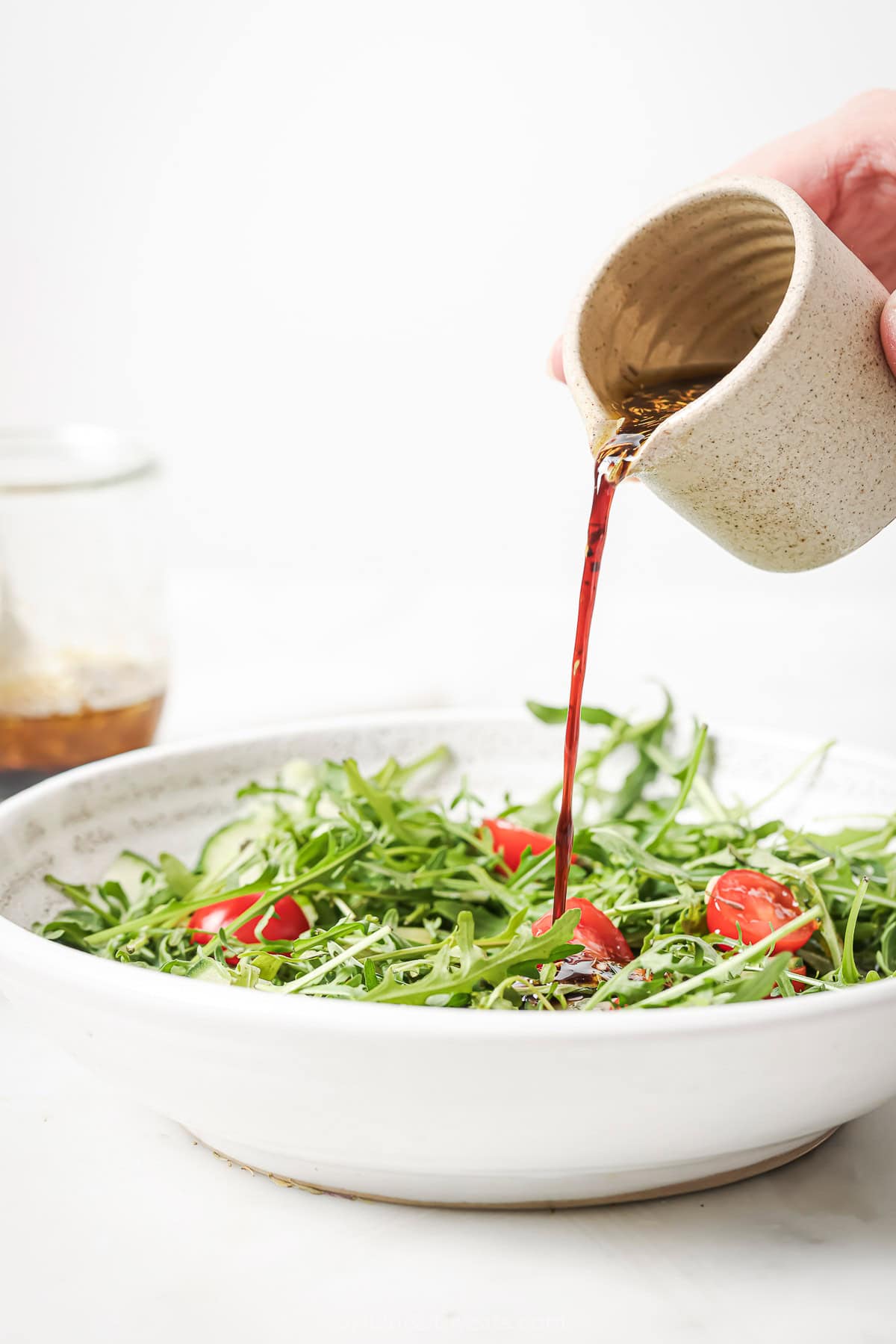 This recipe for balsamic vinaigrette is easy to whip up and the sweet, tangy flavor brings out the best in any salad—and so much more! Pouring balsamic vinaigrette into salad