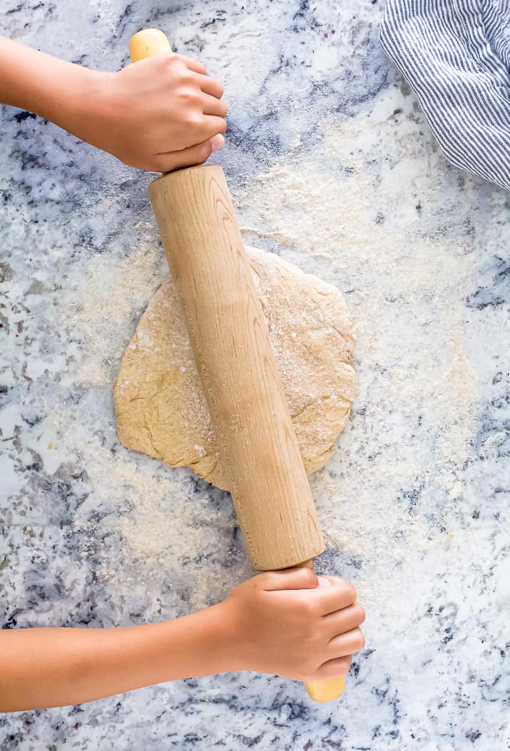 rolling out whole wheat pizza dough on a counter
