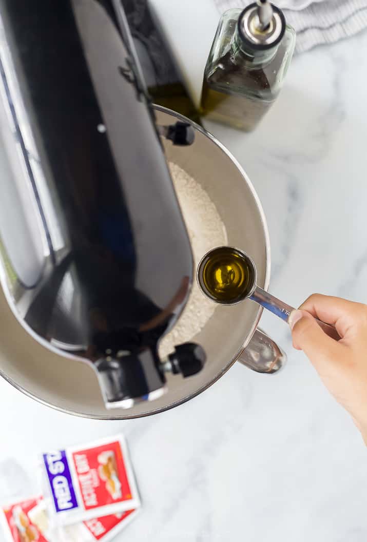pouring olive oil into mixer for pizza dough