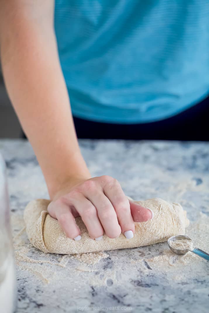 hands rolling out whole wheat pizza dough