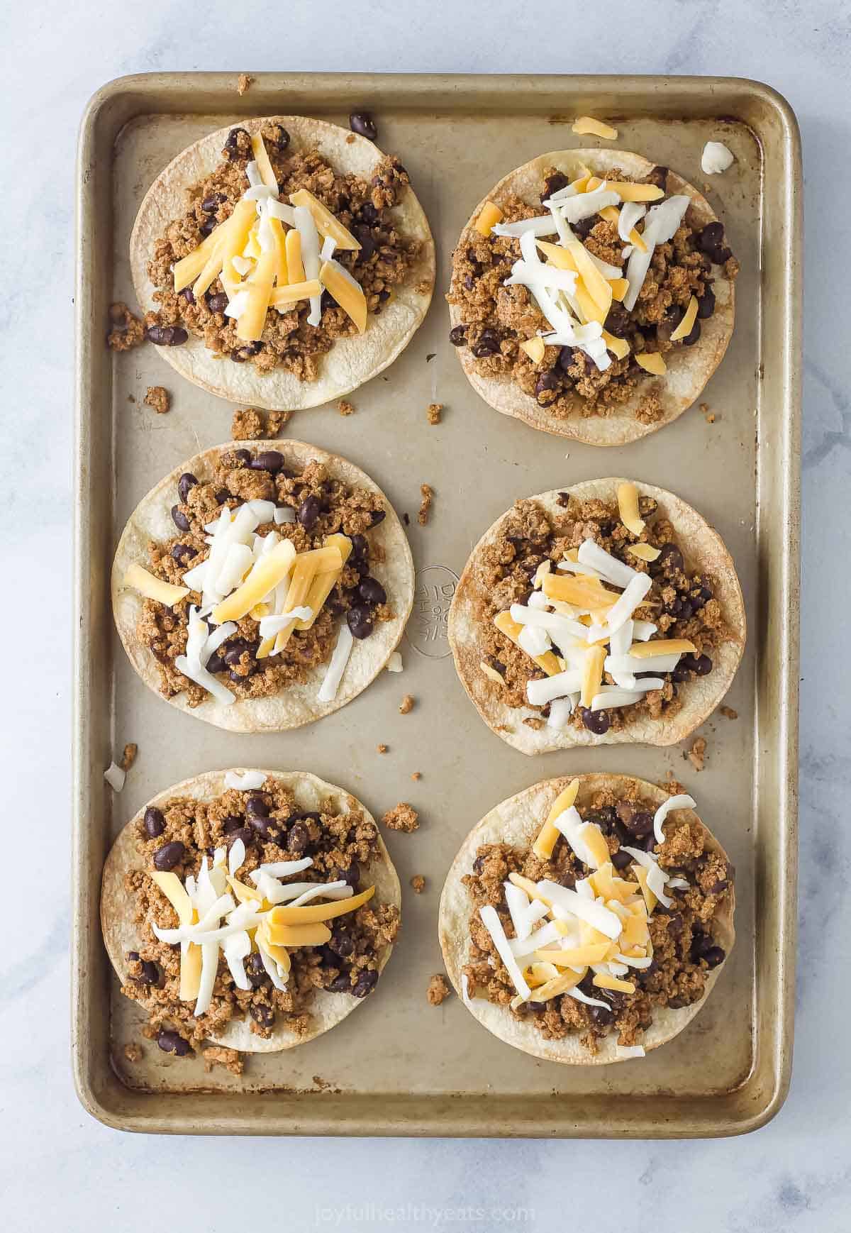 Adding the cheese to the tostadas. 