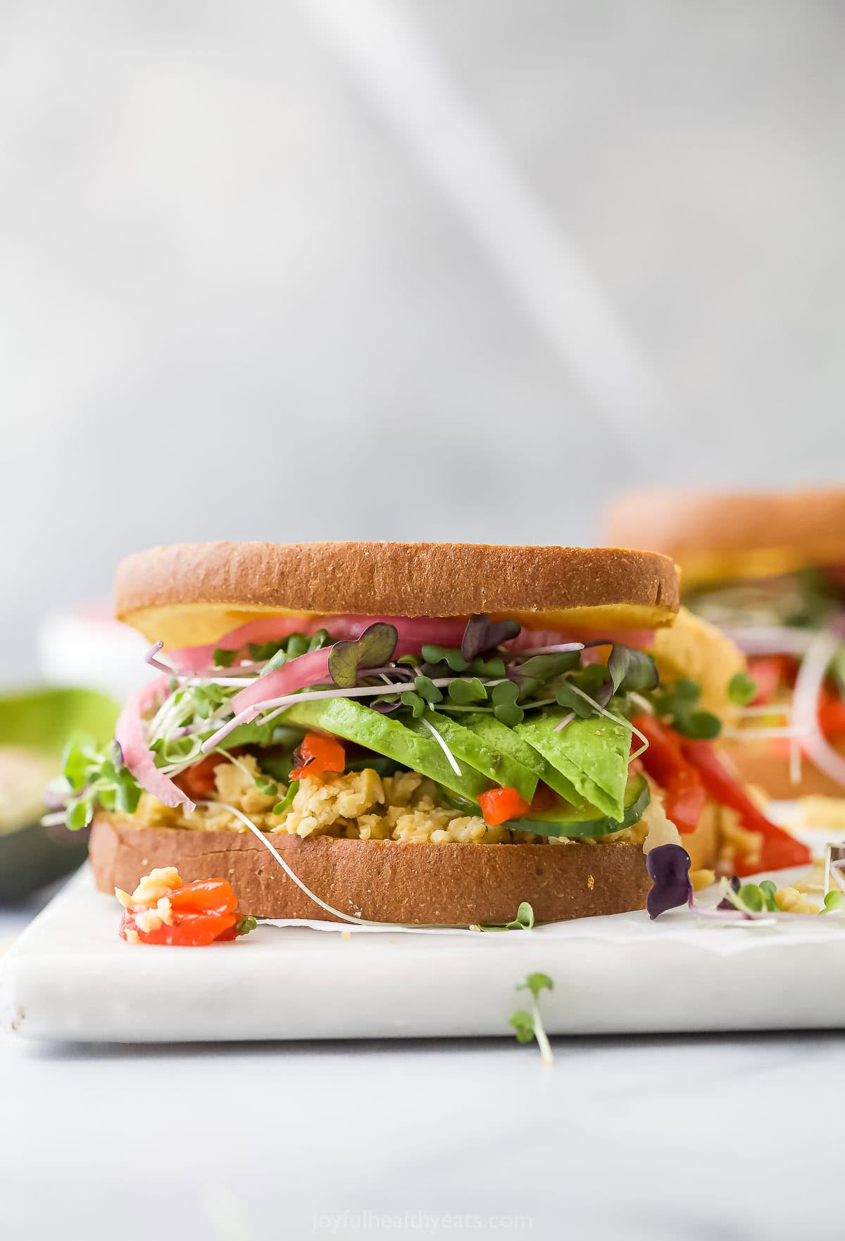 This Avocado Sandwich is the perfect quick lunch, with smashed chickpeas for protein, smoky roasted red peppers, and tangy pickled onions. Avocado sandwich with smashed chickpeas and roasted red peppers