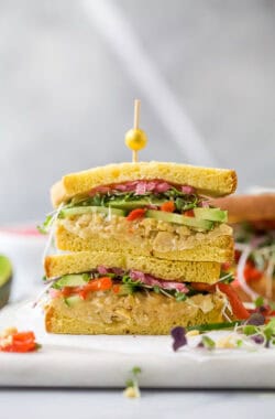 Two avocado sandwich halves stacked with toothpick and olive on top