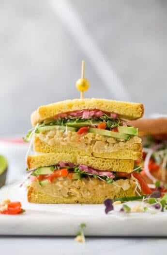 Two avocado sandwich halves stacked with toothpick and olive on top