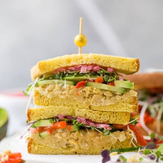 Two avocado sandwich halves stacked with toothpick and olive on top