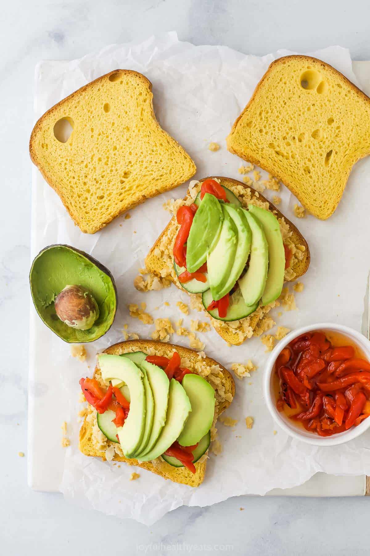 This Avocado Sandwich is the perfect quick lunch, with smashed chickpeas for protein, smoky roasted red peppers, and tangy pickled onions. Avocado slices, smashed chickpeas, and roasted red peppers on two slices of bread for sandwich