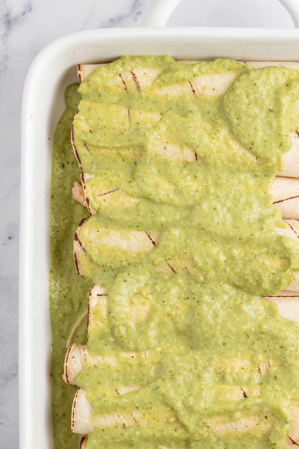 Creamy Chicken Enchiladas Verdes are perfect for big family dinners. They're cheesy and creamy with just the right amount of heat! creamy verde sauce poured over wrapped tortillas