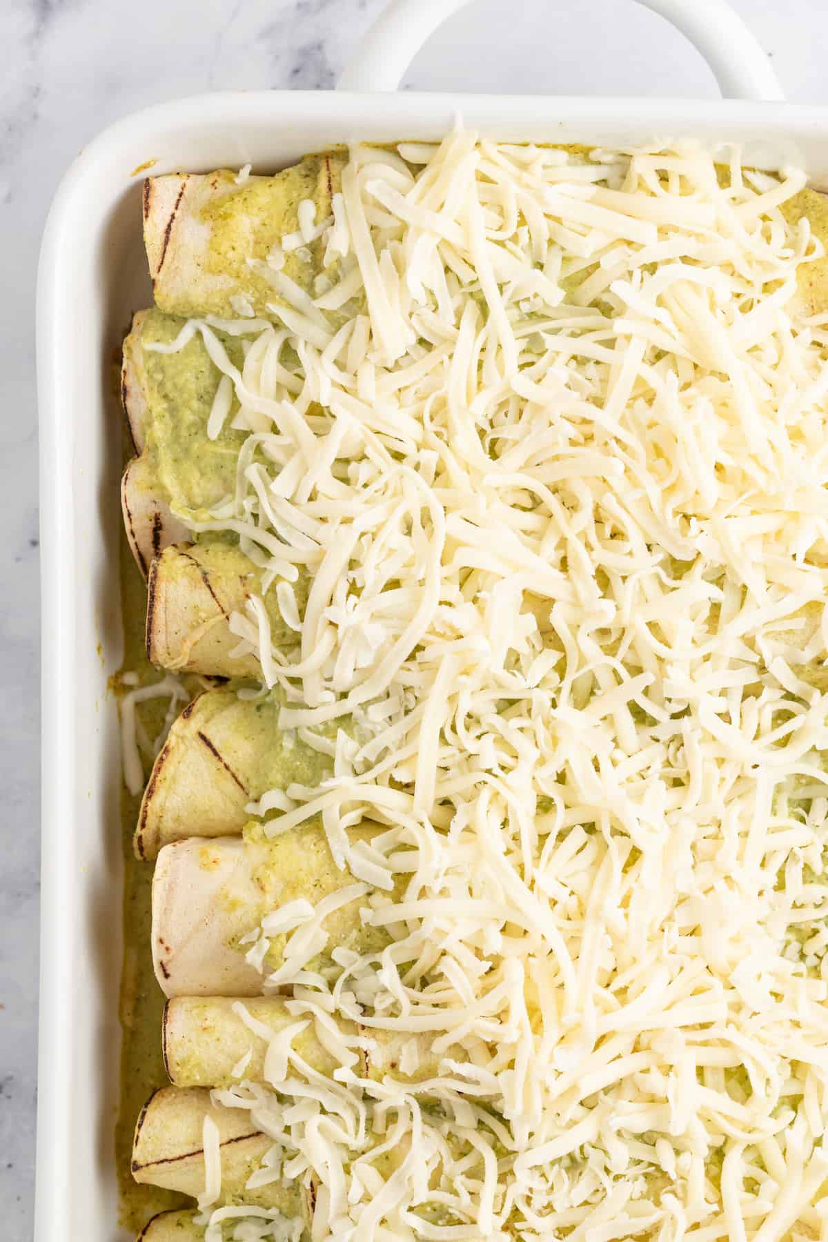 casserole dish with chicken enchiladas and cheese on top