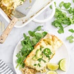 a plate with creamy chicken enchiladas verdes with lime and cilantro garnish