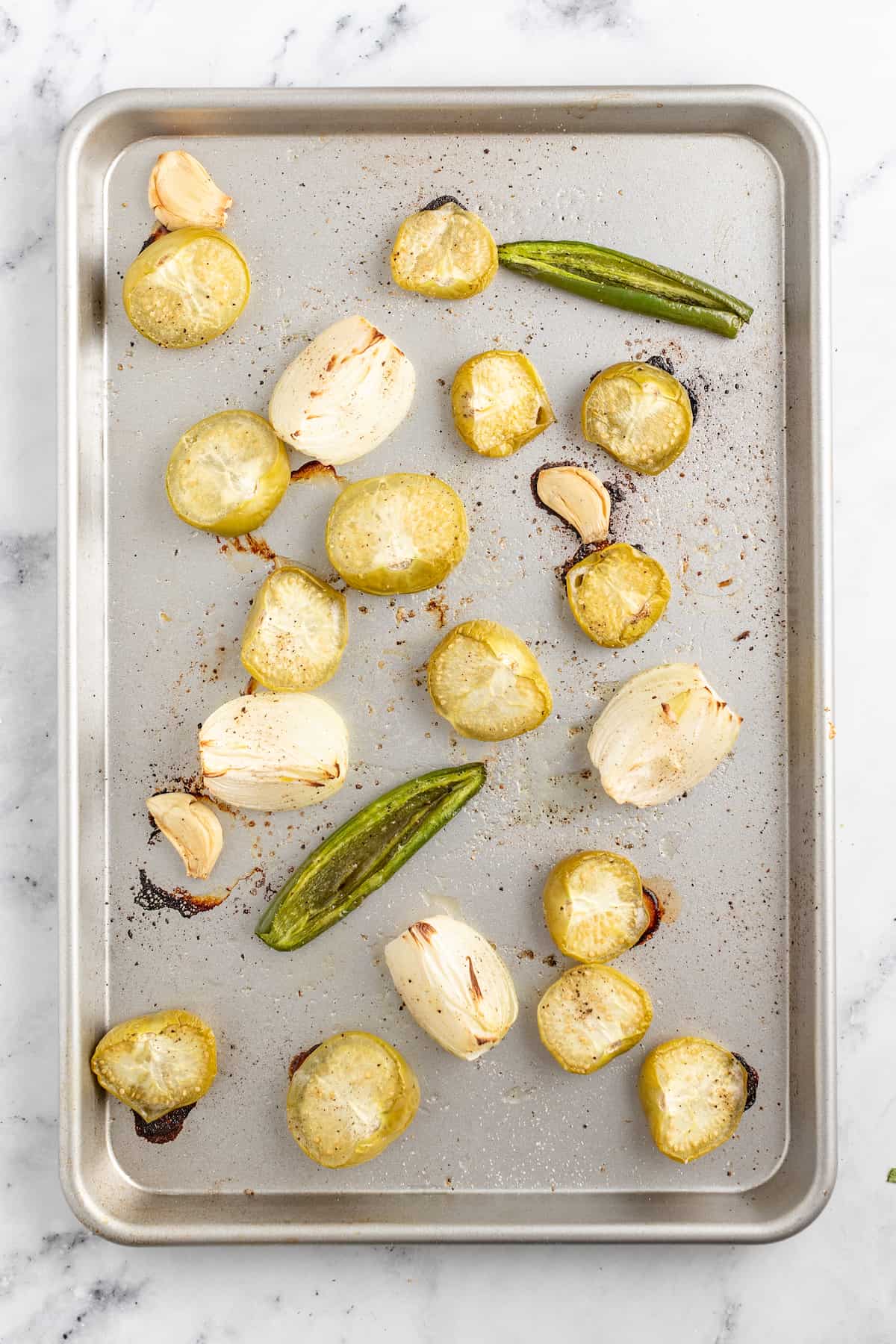 a sheet tray with roasted onions, tomatillos, and jalapenos