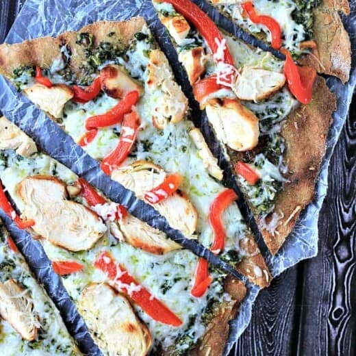 Five Slices of Grilled Chicken Pesto Pizza on a Wooden Surface