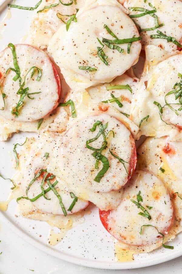 Close-up of caprese-style baked tomatoes with fresh basil on top.