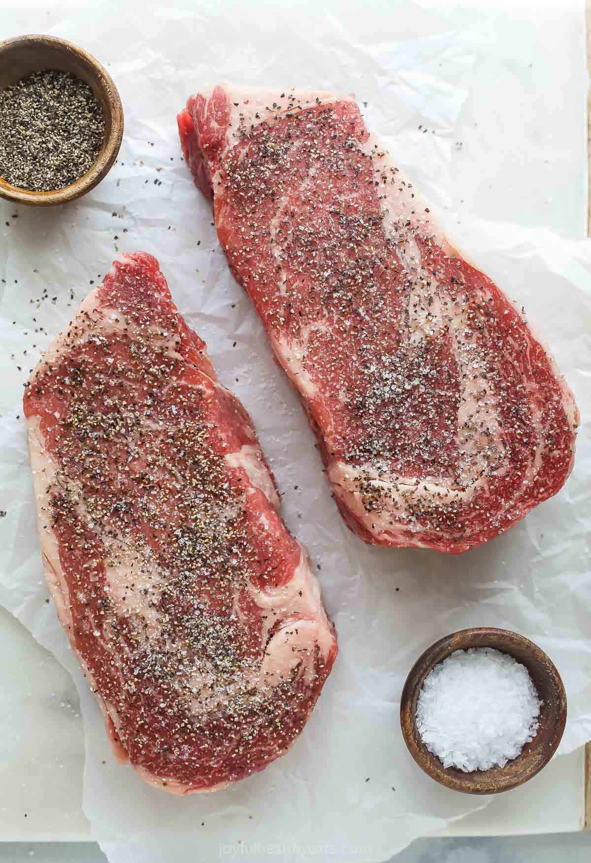 Seasoning the steaks with salt and pepper on all sides.