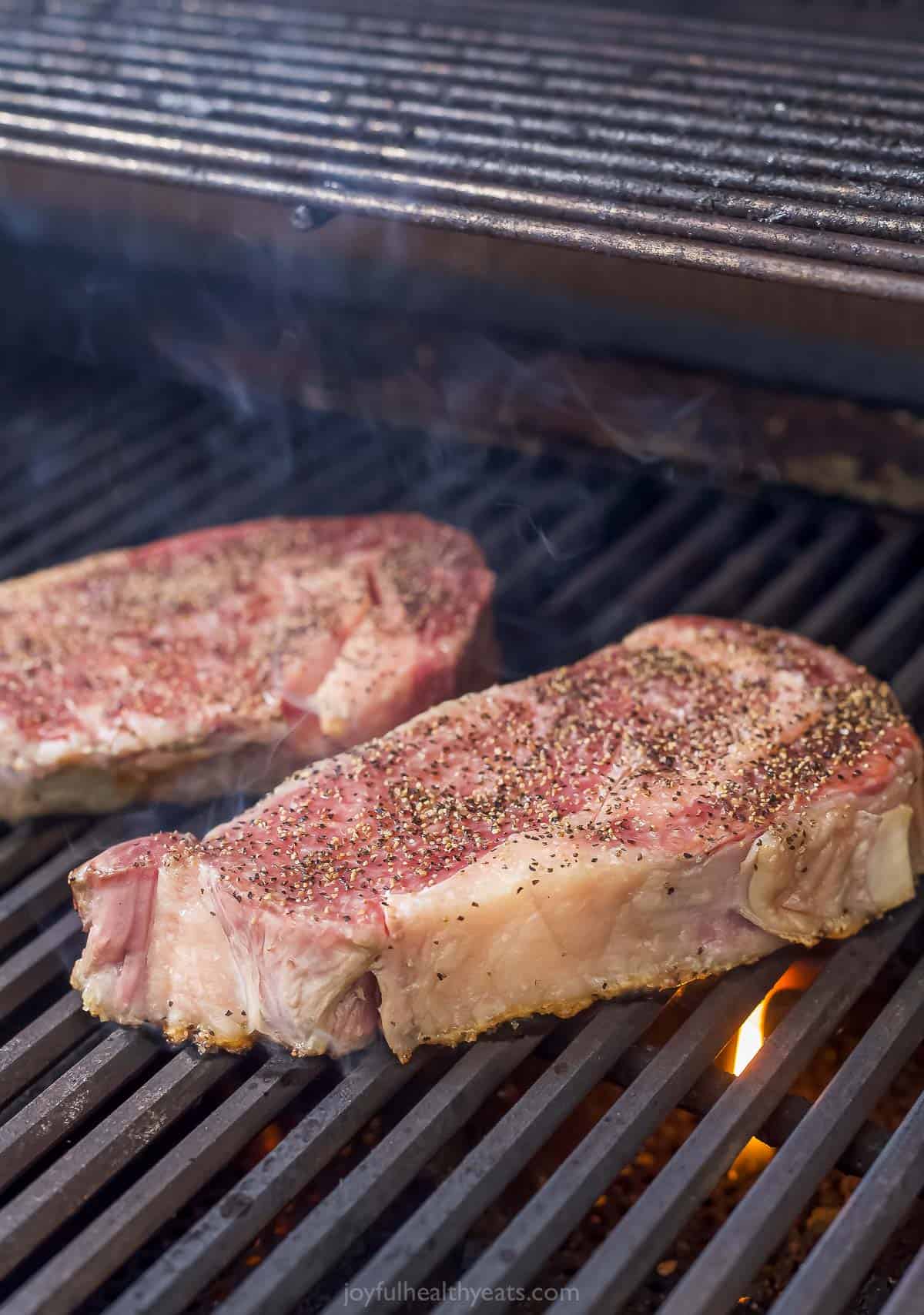 Grilling the seasoned steaks over high heat.