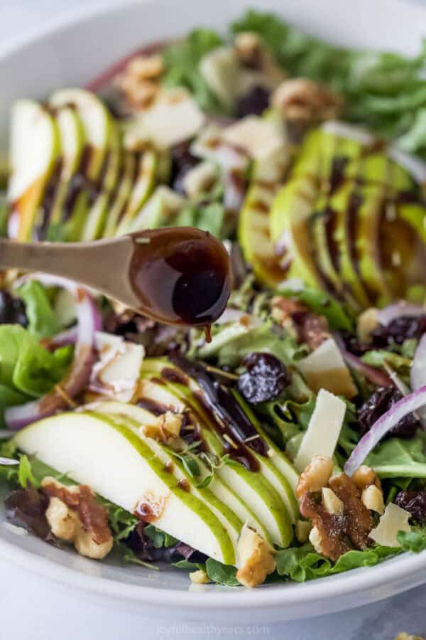 Drizzling balsamic vinaigrette on the salad.
