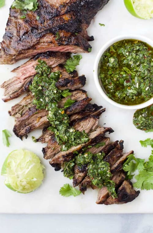 Skirt steak that's been partially sliced topped with chimichurri sauce