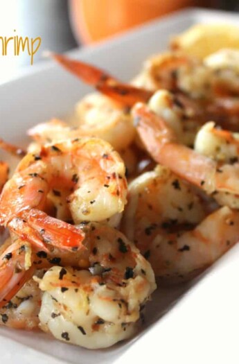 Grilled Garlic Basil Shrimp on a White Serving Plate with Lemon Slices