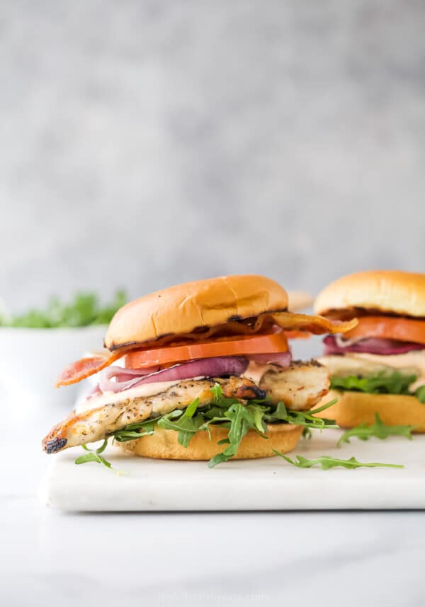 A warm chicken sandwich on French bread with fresh tomatoes, greens, and spicy chipotle mayo.