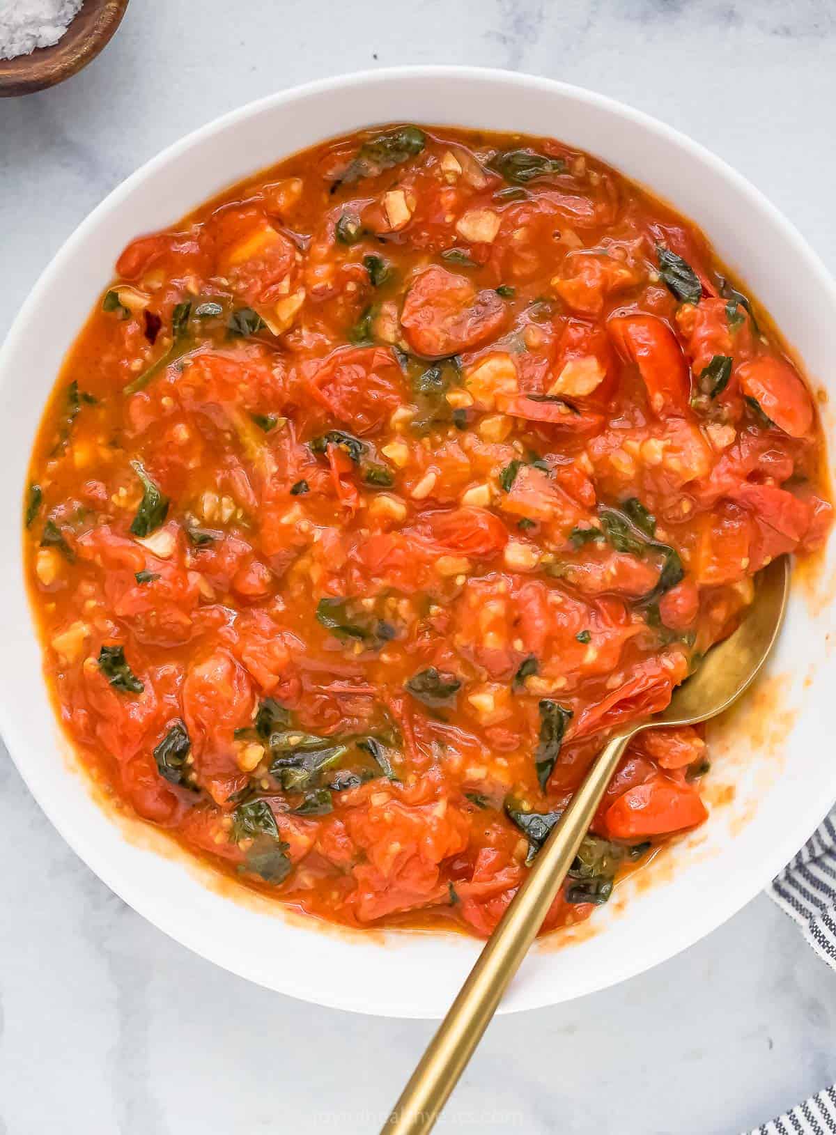 When you got this trusted pasta sauce recipe you will never buy a jar in the store again! Tomatoes, basil and lots of garlic make it delicious. Overhead view of pasta sauce recipe in the bowl with a spoon