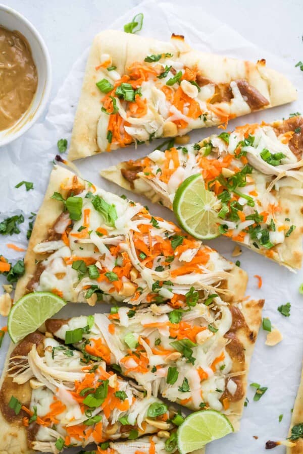 Close-up of cheesy Thai-style pizza with peanut sauce, carrots, and cilantro.