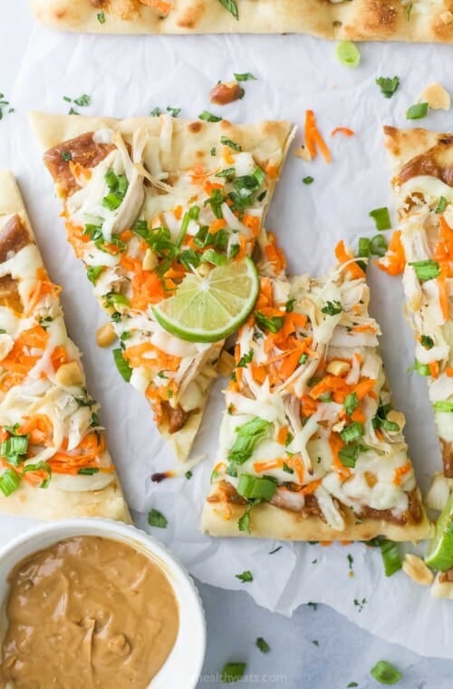 Sliced Thai chicken pizza with fresh cilantro on top.