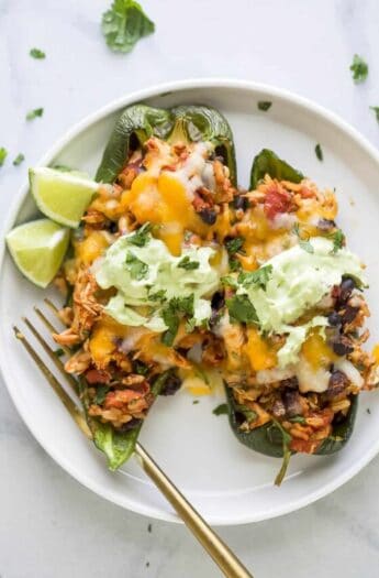 Plate of two stuffed poblano peppers with avocado crema.
