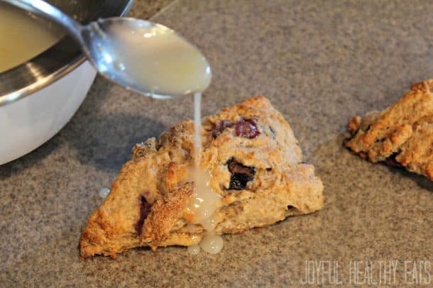 Lemon glaze being drizzled over a Blueberry Lemon Scone