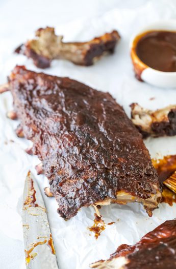 bbq baby back ribs on a board with a bowl of bbq sauce