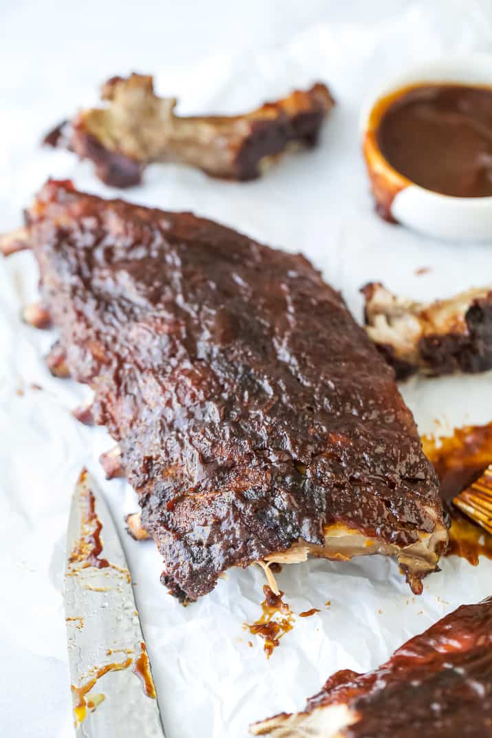 bbq baby back ribs on a board with a bowl of bbq sauce