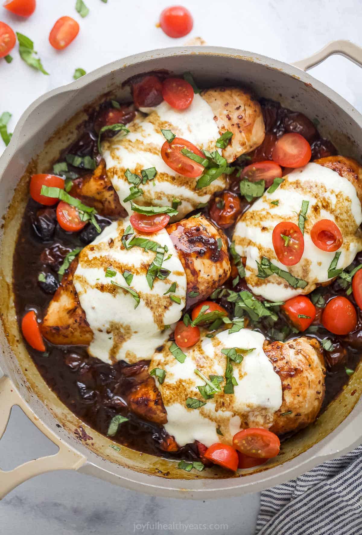 Skillet of caprese chicken with melty cheese. 