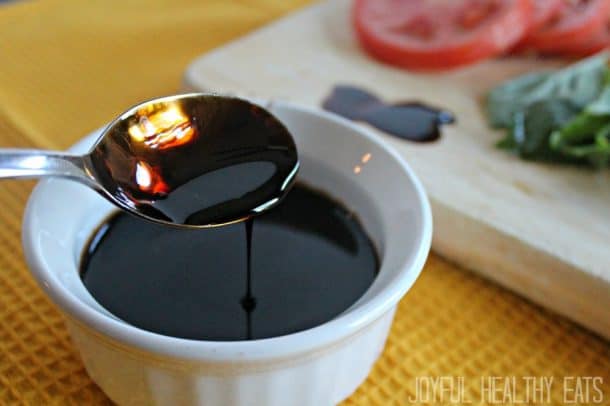 Balsamic Reduction in a White Container Beside a Wooden Cutting Board
