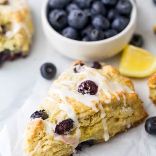 Close-up of a flaky lemon blueberry scone with glaze.