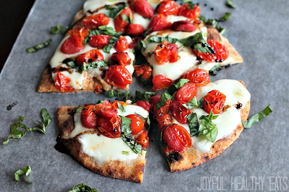 Caprese flatbread on parchment paper cut into 4 pieces