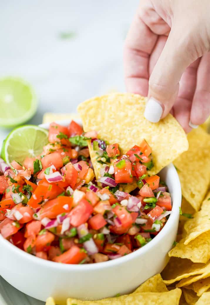 a chip scooping fresh pico de gallo