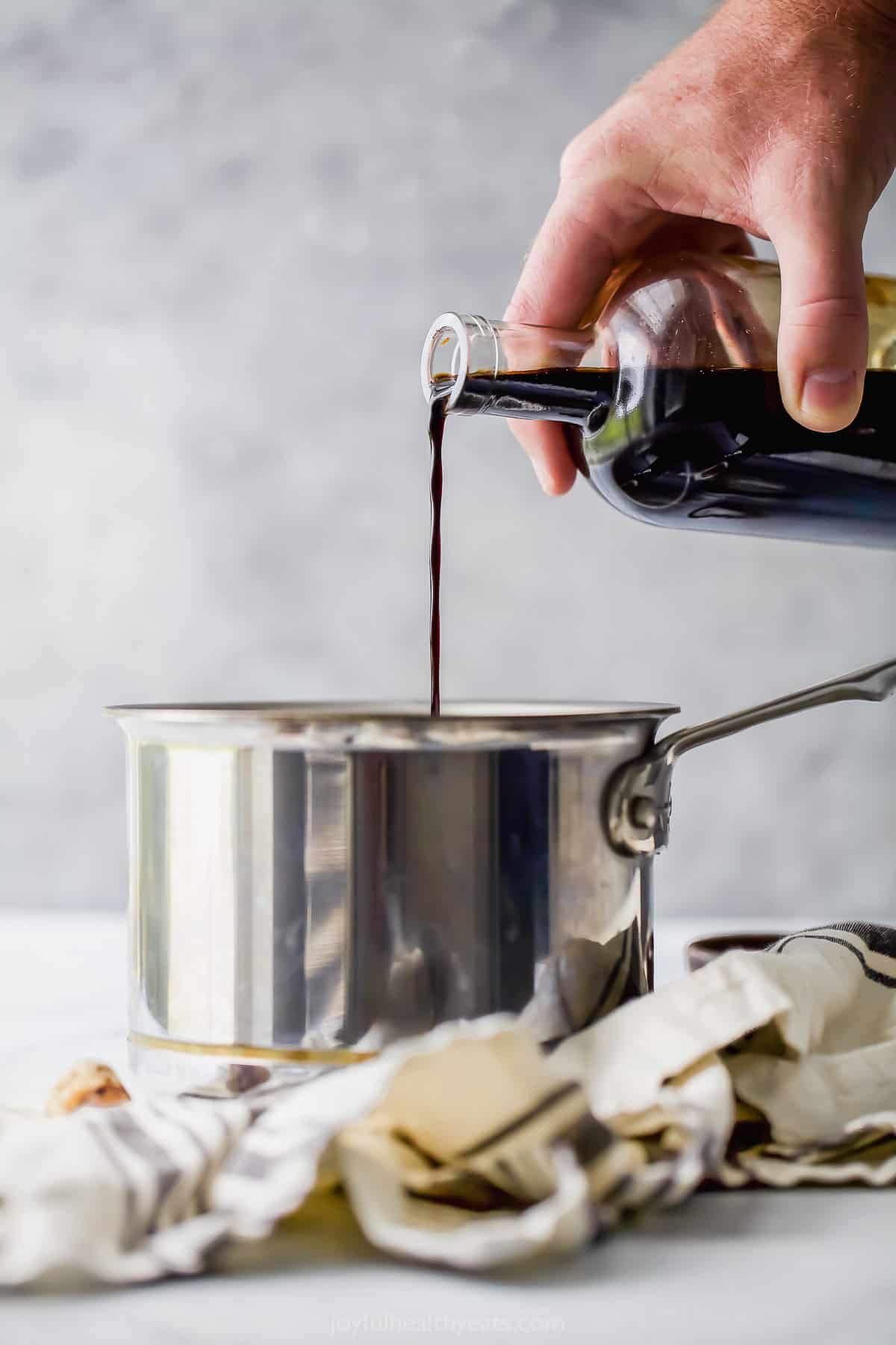 Pouring balsamic vinegar into a pot.
