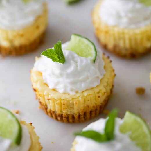 Mini key lime pies garnished with whipped cream, fresh mint, and slice of lime
