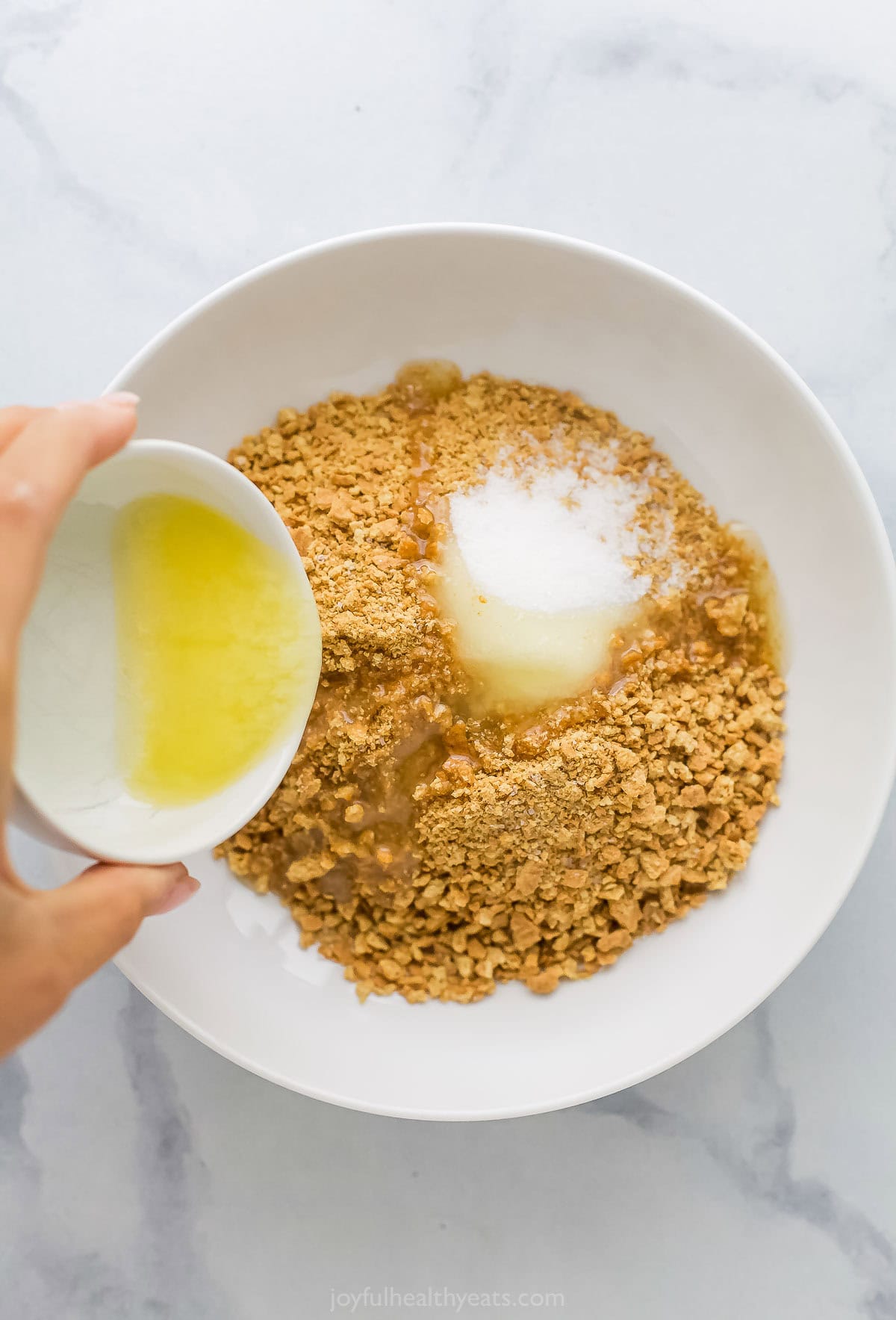 Tart and sweet, creamy and fluffy, these mini key lime pies are a delightful one-bite dessert to whip up for parties—and just because. Pouring butter into bowl of ingredients for graham cracker crust