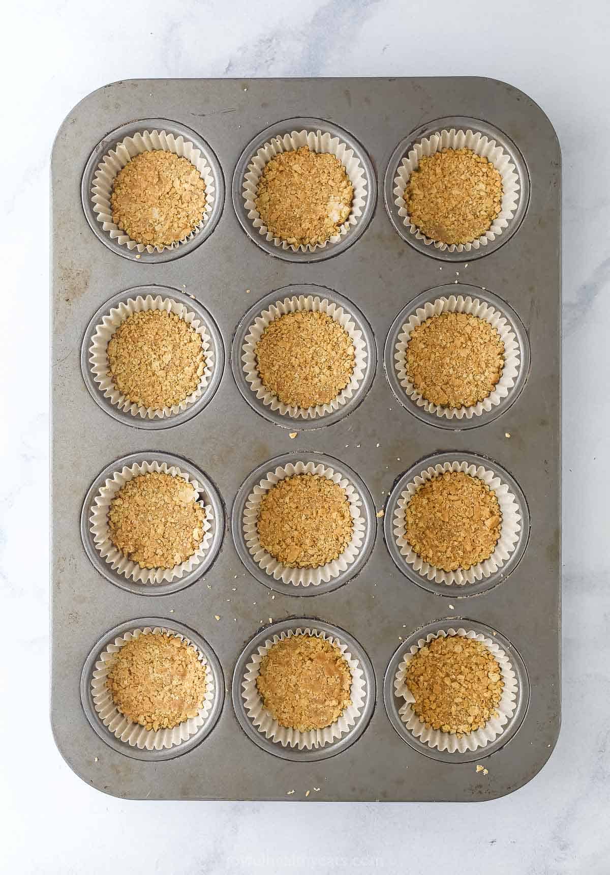 Tart and sweet, creamy and fluffy, these mini key lime pies are a delightful one-bite dessert to whip up for parties—and just because. Overhead view of graham cracker crust in cupcake wrappers in muffin pan