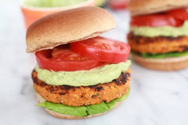 A sweet potato burger on a bun with avocado, tomato and avocado ranch sauce