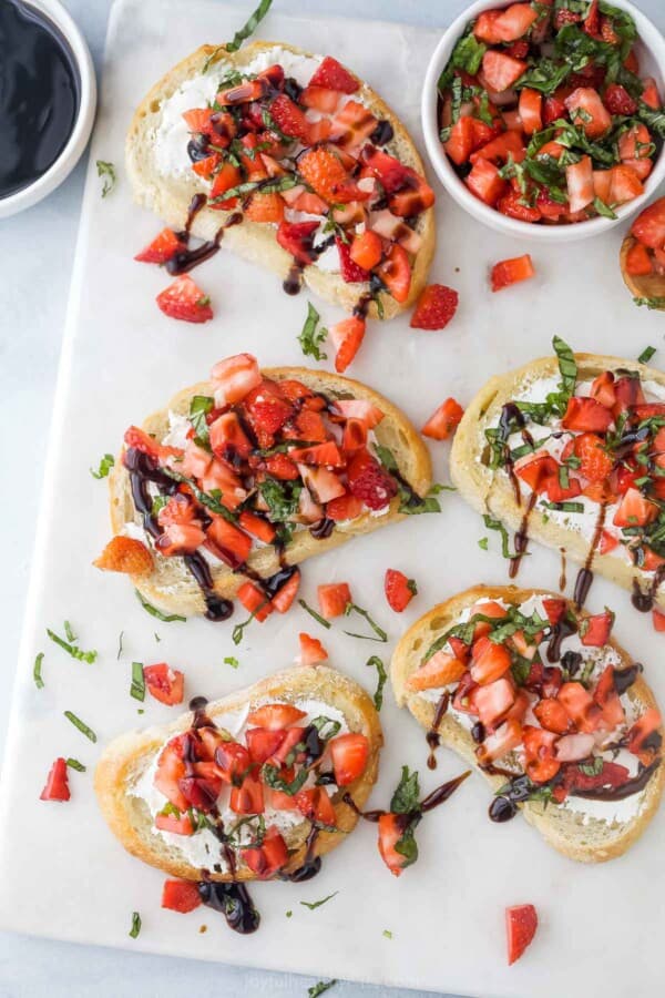 Strawberry bruschettas on a marble charcuterie board.