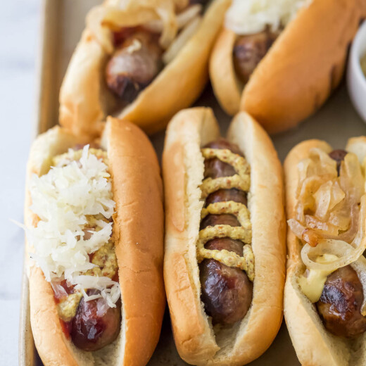 Lager-infused beer brats in toasted buns with spicy mustard, sauerkraut, and onions.