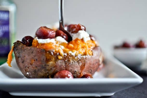 Roasted sweet potato topped with grapes and goat cheese on a plate