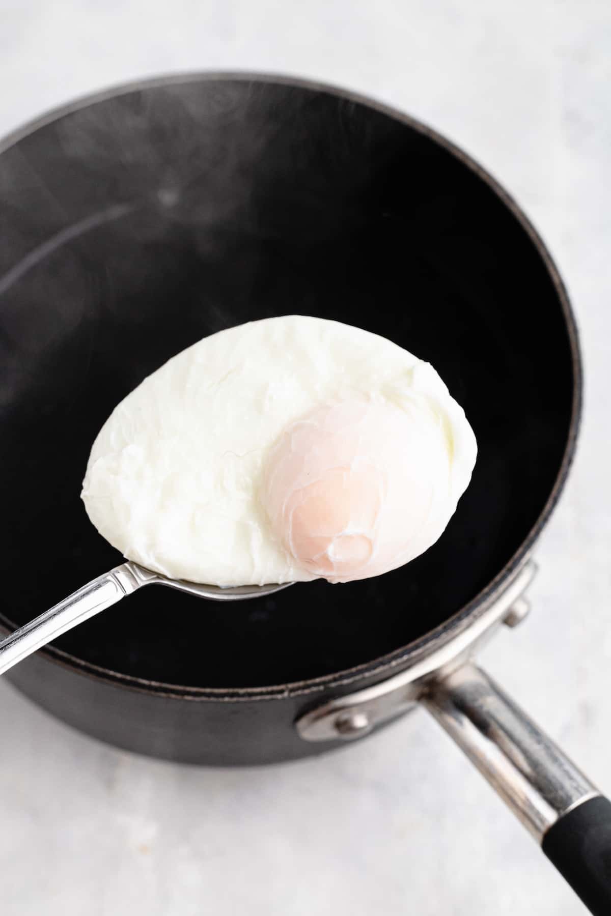 A poached egg being scooped out of water