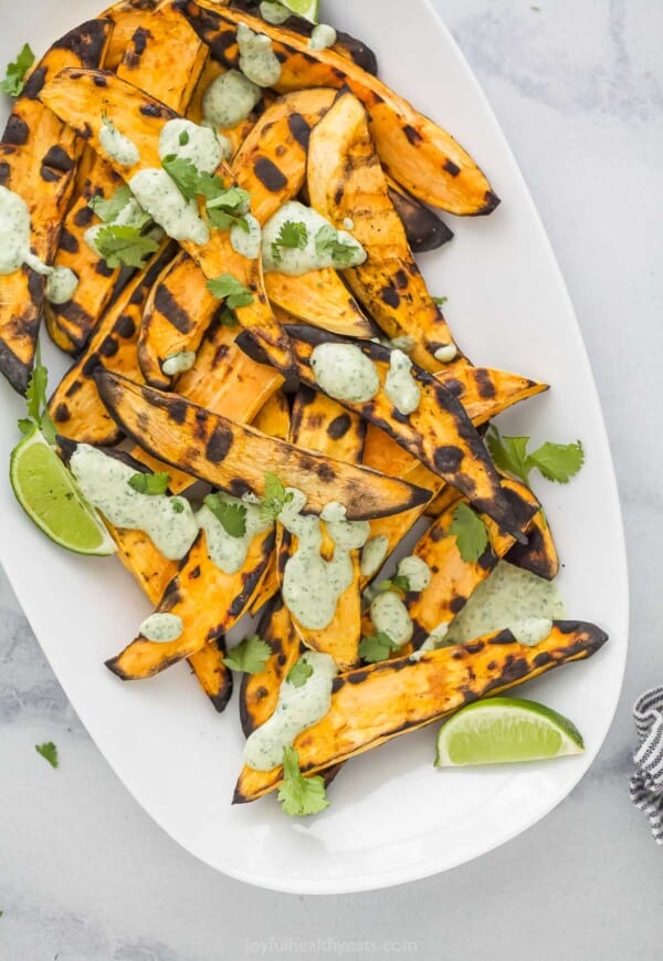Plate of grilled sweet potatoes drizzled with lime cilantro crema.