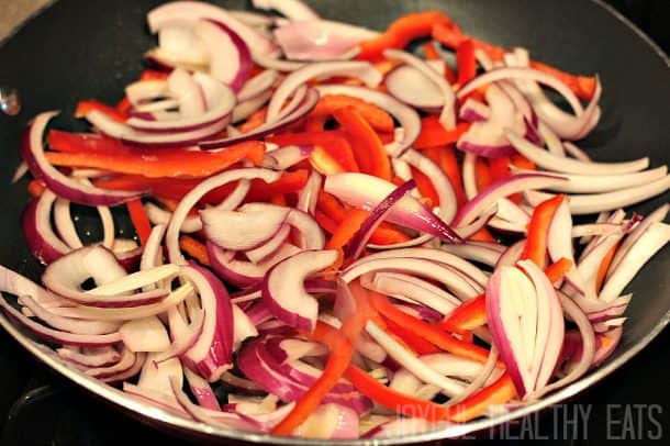 Fresh peppers and onions being cooked in a pan